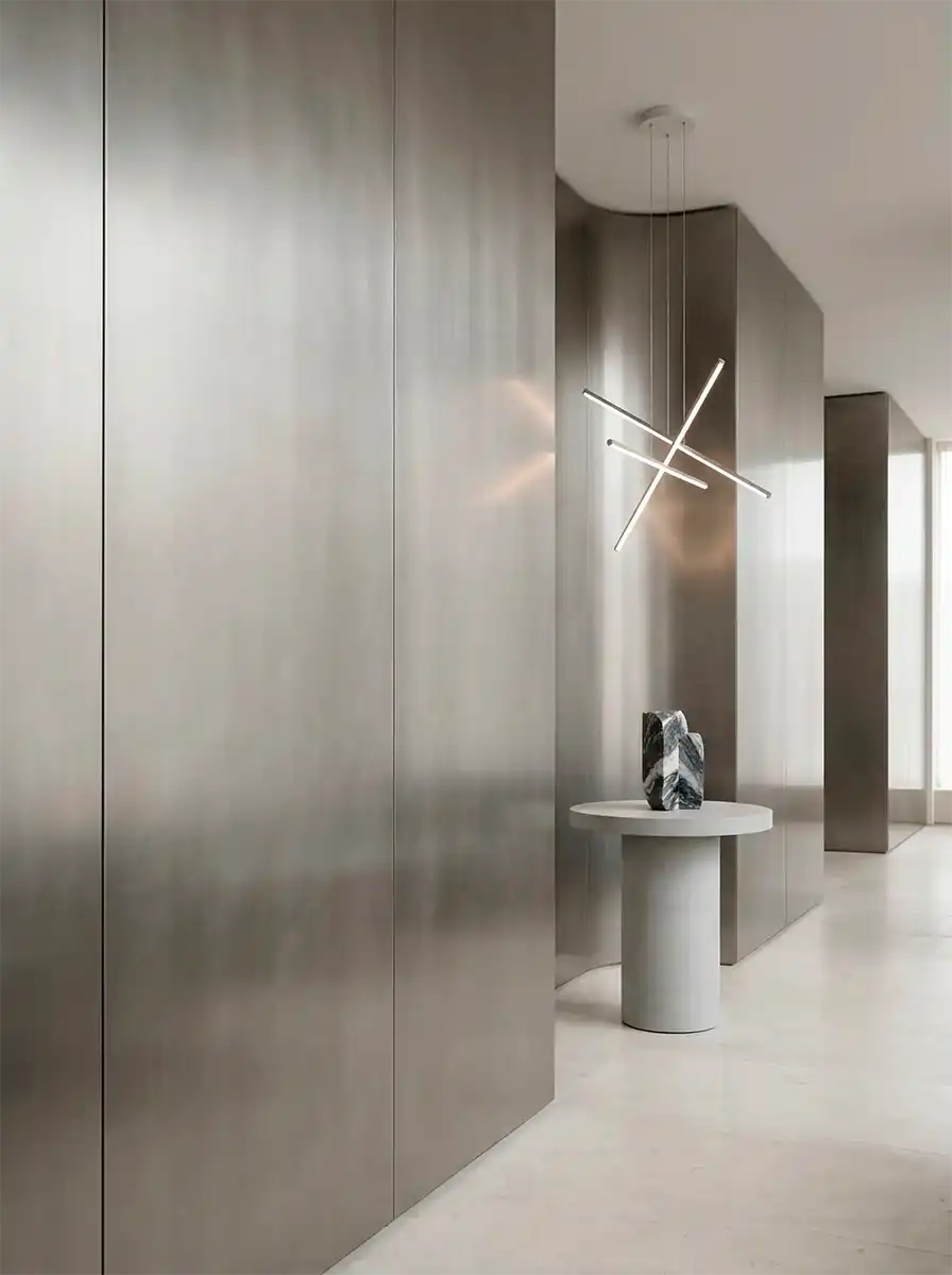 Современный интерьер с обоями под металл, подвесным светильником и круглым столиком.